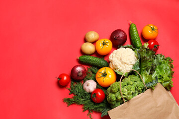 Delivery of vegetarian products. Bag with different vegetables on red background, top view