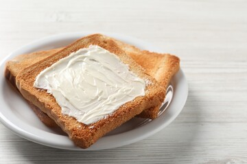 Delicious toasted bread slices with butter on white wooden table, closeup