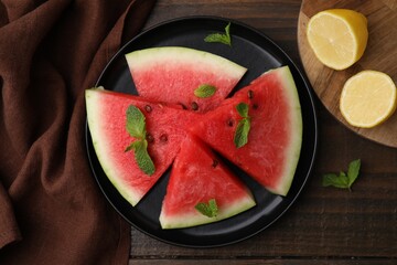 Fresh watermelon slices with mint leaves and lemon on wooden table, flat lay