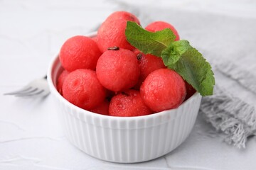 Tasty watermelon balls with mint in bowl on white table, closeup