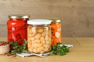 Different pickled products in jars and spices on wooden table