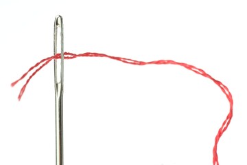 Sewing needle with red thread on white background, closeup