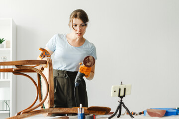 Carpenter restoring old wooden chair using electric sander and recording diy video blog