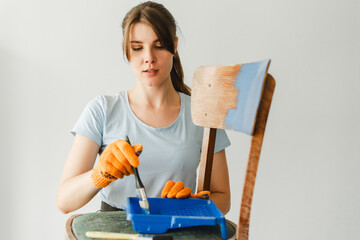 Woman concentrating while painting a chair at home