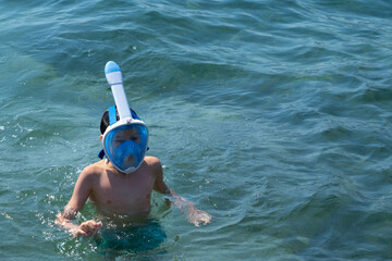Teenage boy enjoying snorkeling in sea water, enjoying active summer holidays, exploring underwater...