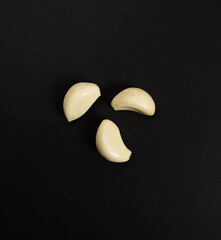 Garlic cloves photographed on a black background, top view Garlic cloves