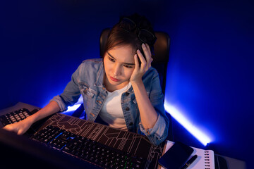 Stressful young beautiful asian creative looking on pc to search project creator social media online with planning channel strategy reach of more viewer home at neon modern office at night. Stratagem.