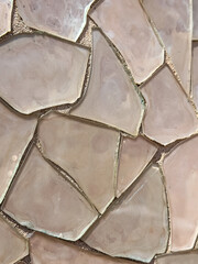 Mosaic tile design with broken pieces in different size in a light pink tones.