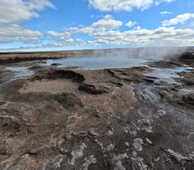Steaming Geothermal Springs in Iceland with a Rugged Landscape and Fluffy Clouds
