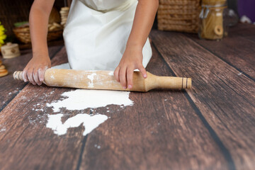 child with rolling pin in hand. little chef playing with food
