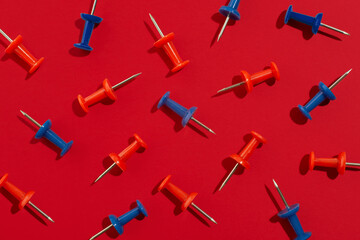 Red and blue stationery pins on red background. Back to school concept