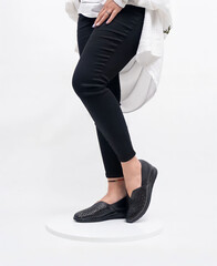 Female with black loafer pump shoes on leg. Women's footwear and outfit concept. Black leather loafer shoes and female.