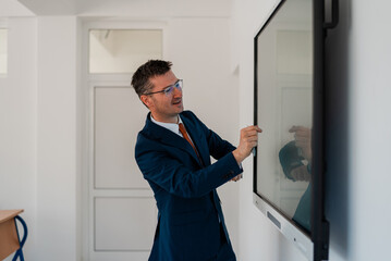 University male teacher giving lecture in the classroom or business man presenter public speaking in a conference meeting room using a display screen board.