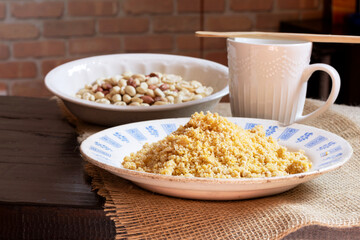 Homemade peanut brittle in an old plate with signs of age next to a mug on top of a rustic tablecloth