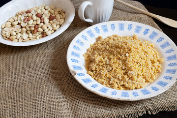 Homemade peanut brittle, like farofa, inside an old porcelain plate with signs of age, photographed from top to bottom