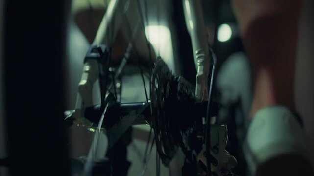 A cyclist is doing a cycling workout on a special indoor exercise machine. Carrying out a cycling exercise plan, preparing for a cycling competition. The athlete pedals, trains