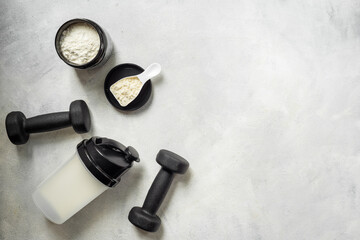 Sports nutrition - protein shaker and black dumbbells, top view