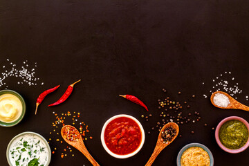Set of sauces in bowls with spices in spoons and ingredients, top view