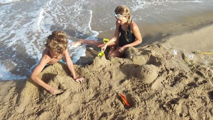 children play with sand on the seashore. family on vacation spends time on the beach.