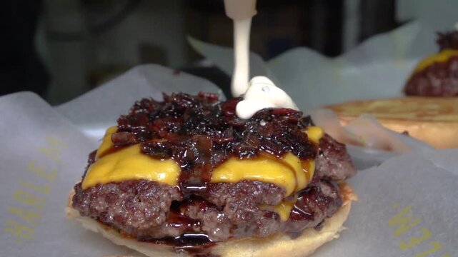chef making doble smashed burger with bacon jam and mayo