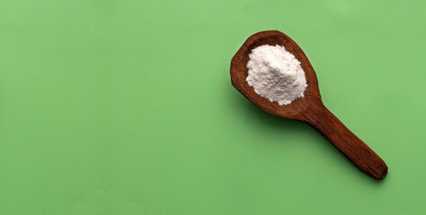 Baking soda powder in spoon - Healthy food. Green background