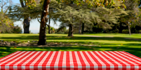 A checkered red and white picnic table with a view of trees and grass