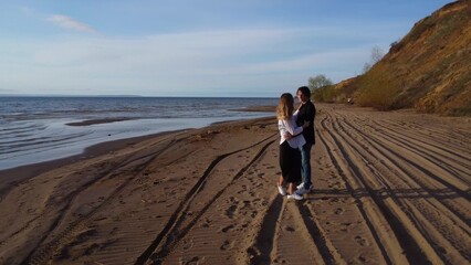 Young couple in love walking on the beach and spinning holding hands. Aerial view of the beach. 4k