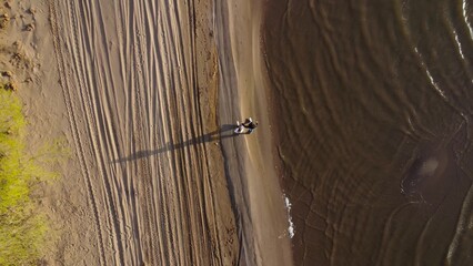 Young couple in love walking hand in hand on the beach from a bird's eye view. Drone shot.