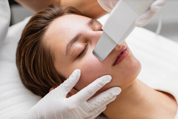 Female receiving a facial treatment with a handheld device in a spa during the day