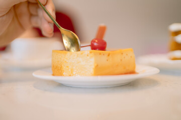Woman eating creme caramel with cherry topping in coffee shop