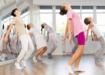 Obraz premium During group lesson, positive smiling girl dances, trains to perform modern jazz. Educational classes for teenagers, modern dancing, active hobbies