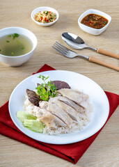 Steamed rice topped with chicken on the wooden table
