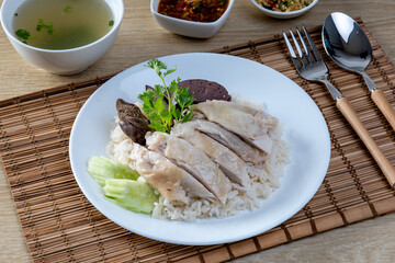 Steamed rice topped with chicken on the wooden table