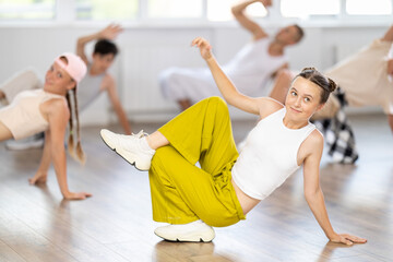 Obraz premium During workout, teenage student girl dances hip hop with friends, learning to dance. Followers look closely at obscure teacher, follow instructions, repeat movements, dance elements