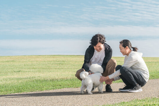 公園で犬の散歩をする愛犬家の夫婦・家族・ファミリー（中年・ミドル）
