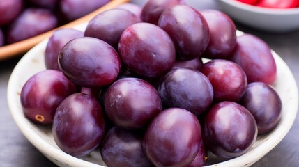 Fototapeta premium Fresh ripe plums on elegant white dish, showcasing fruits in beautifully arranged presentation