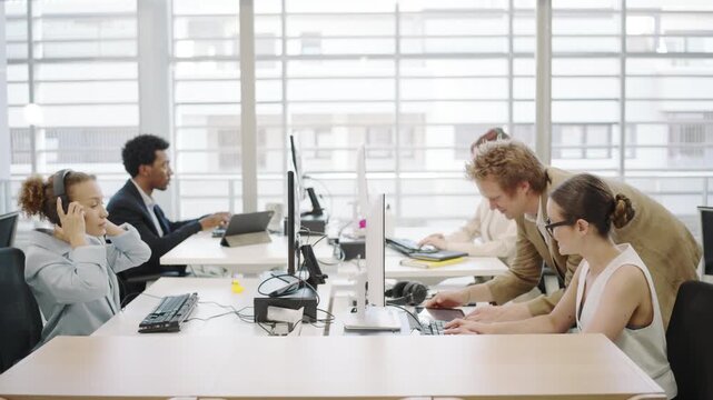 In a modern office environment, a diverse team of ambitious young professionals collaborate using technology to achieve business success through innovation and effective communication and teamwork
