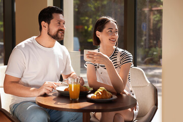 Happy couple having tasty breakfast in cafe