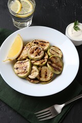 Tasty grilled zucchini slices served on black table, above view