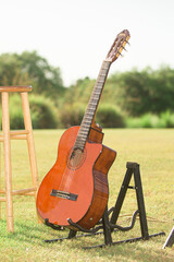 Wood violin guitar on guitat stan on green grass at beautiful wedding
