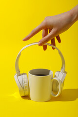 A cup of tea with headphones on a yellow background