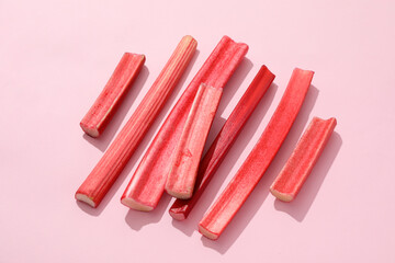 Fresh stalks of rhubarb on a pink background