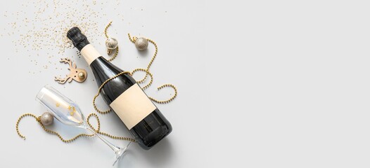 Bottle of champagne, glass and Christmas decorations on light background with space for text