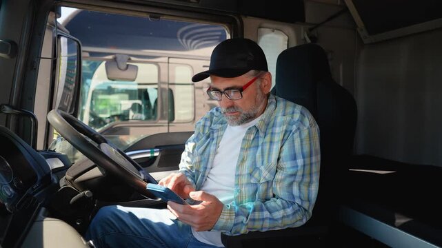 Senior truck driver using truck gps navigation to looks the route before leaving. Right hand drive car