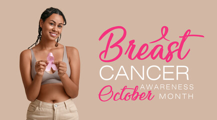 Young African-American woman with pink ribbon on beige background. Breast cancer awareness concept