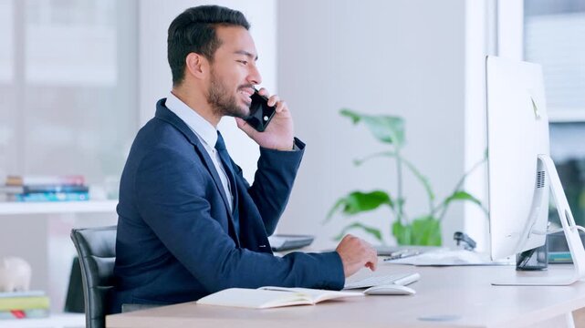 Young corporate executive and professional communicating project plans and discussing deals with clients in a company. Business man talking on a phone while working on a computer in an office.