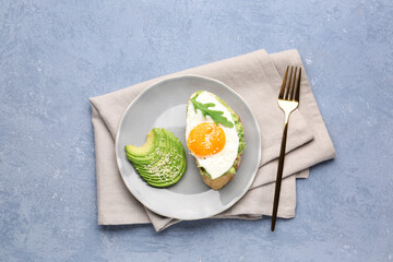 Plate of tasty bruschetta with avocado and egg on grey background