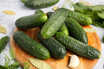 Wooden board with fresh cucumbers for preservation on table, closeup