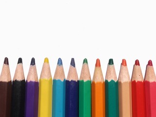 A set of colored pencils drawing pencils are on the background of a white, partially empty room