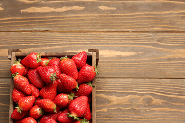 Box with fresh strawberries on wooden background
